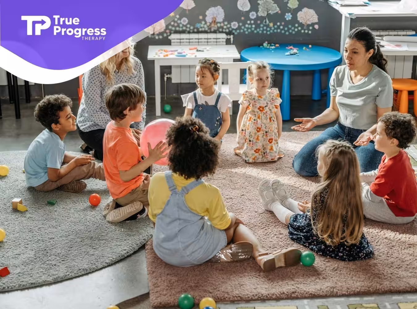 Group of autistic children and two ABA therapists sitting in a circle on rugs at a classroom in New Jersey.
