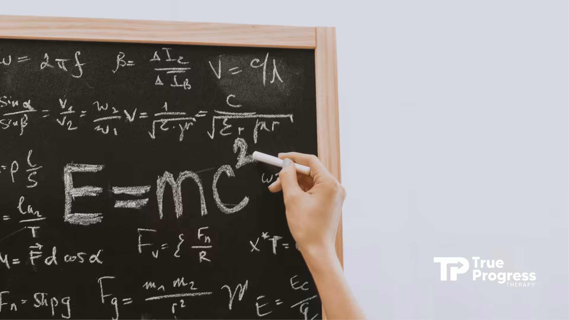 Hand writing E=mc² equations with chalk on blackboard, favorite subject by autistic Sheldon Cooper.