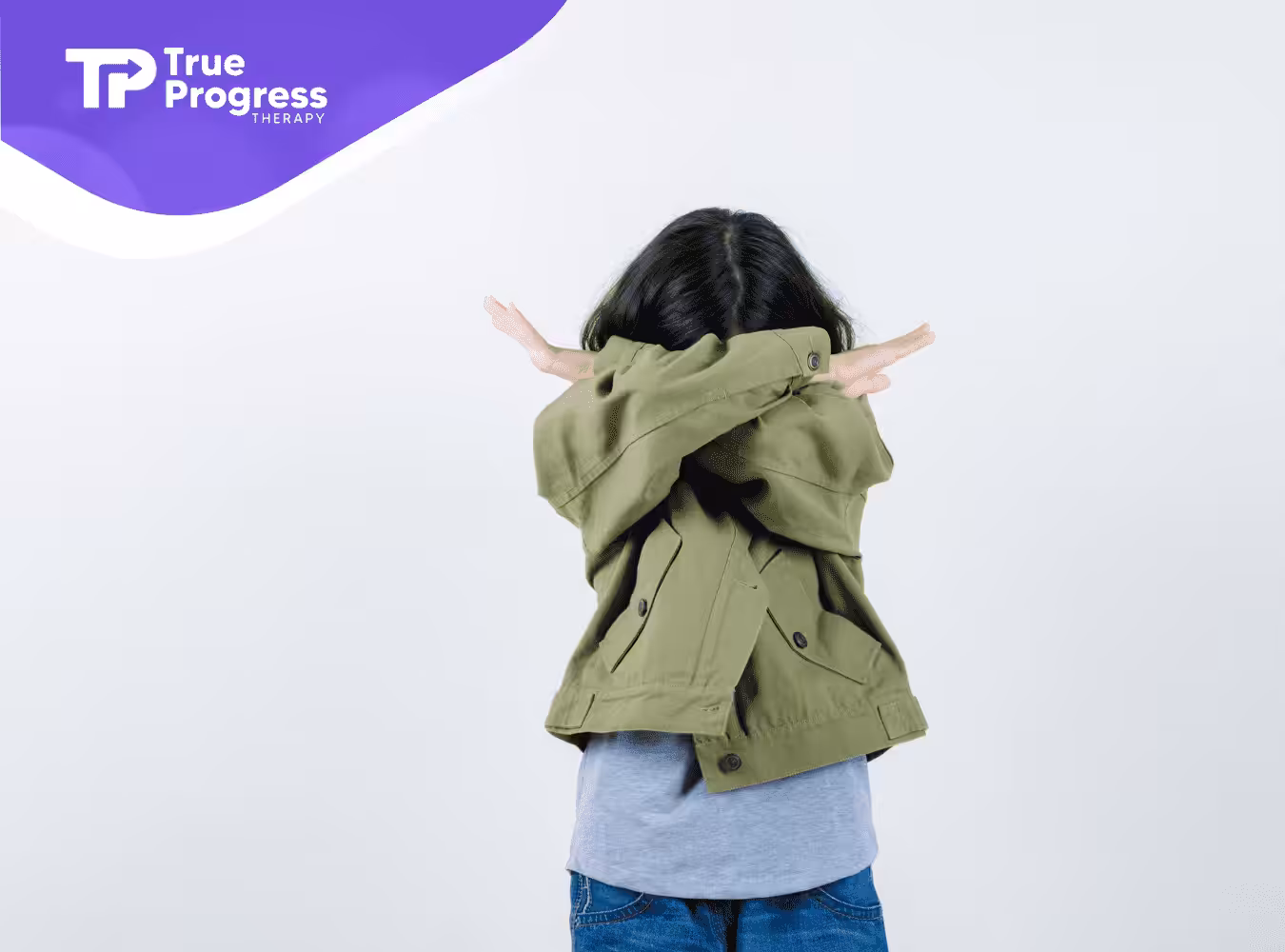 A child with autism covering her face with her arms.