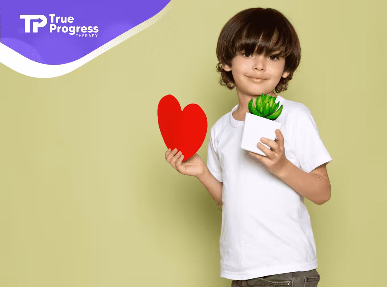 A kid standing in front of a green background holding a cutout of a heart and a plant