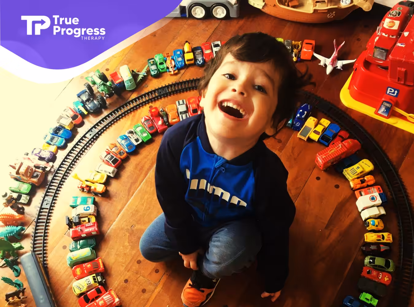 A kid with his train toys smiling