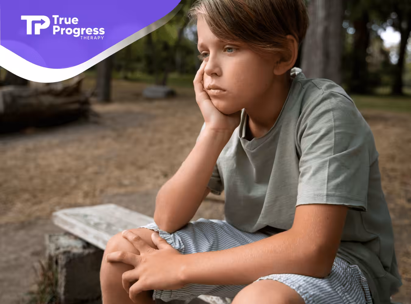 A kid with autism sitting alone outdoors