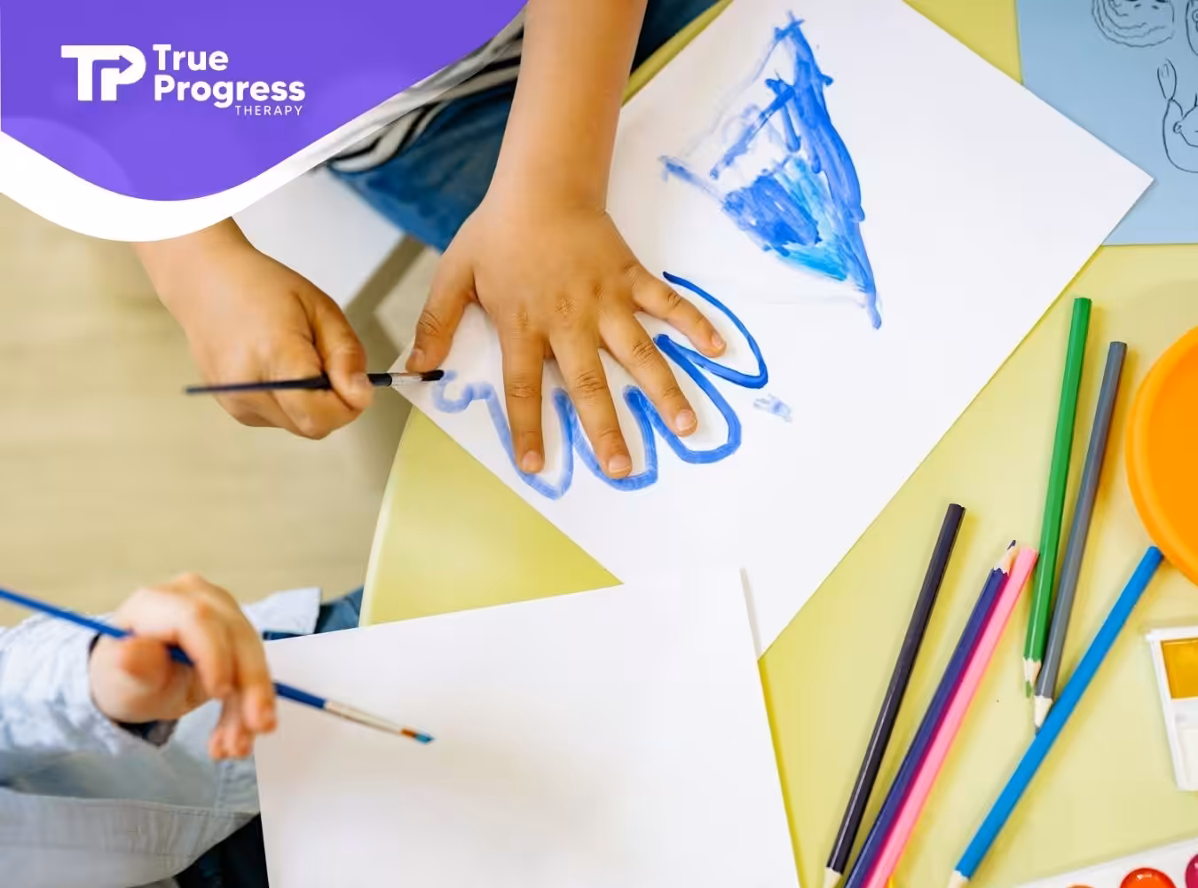 Close-up of autistic children painting on paper with brushes and paints at a table in New Jersey.