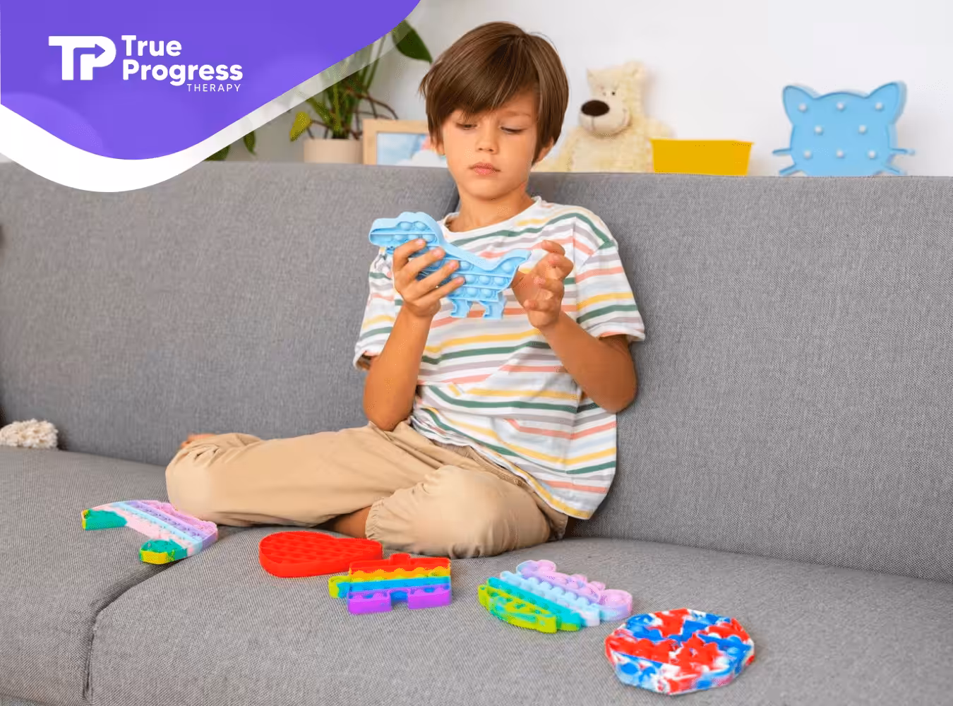 A boy sitting on a couch playing with colorful fidget toys