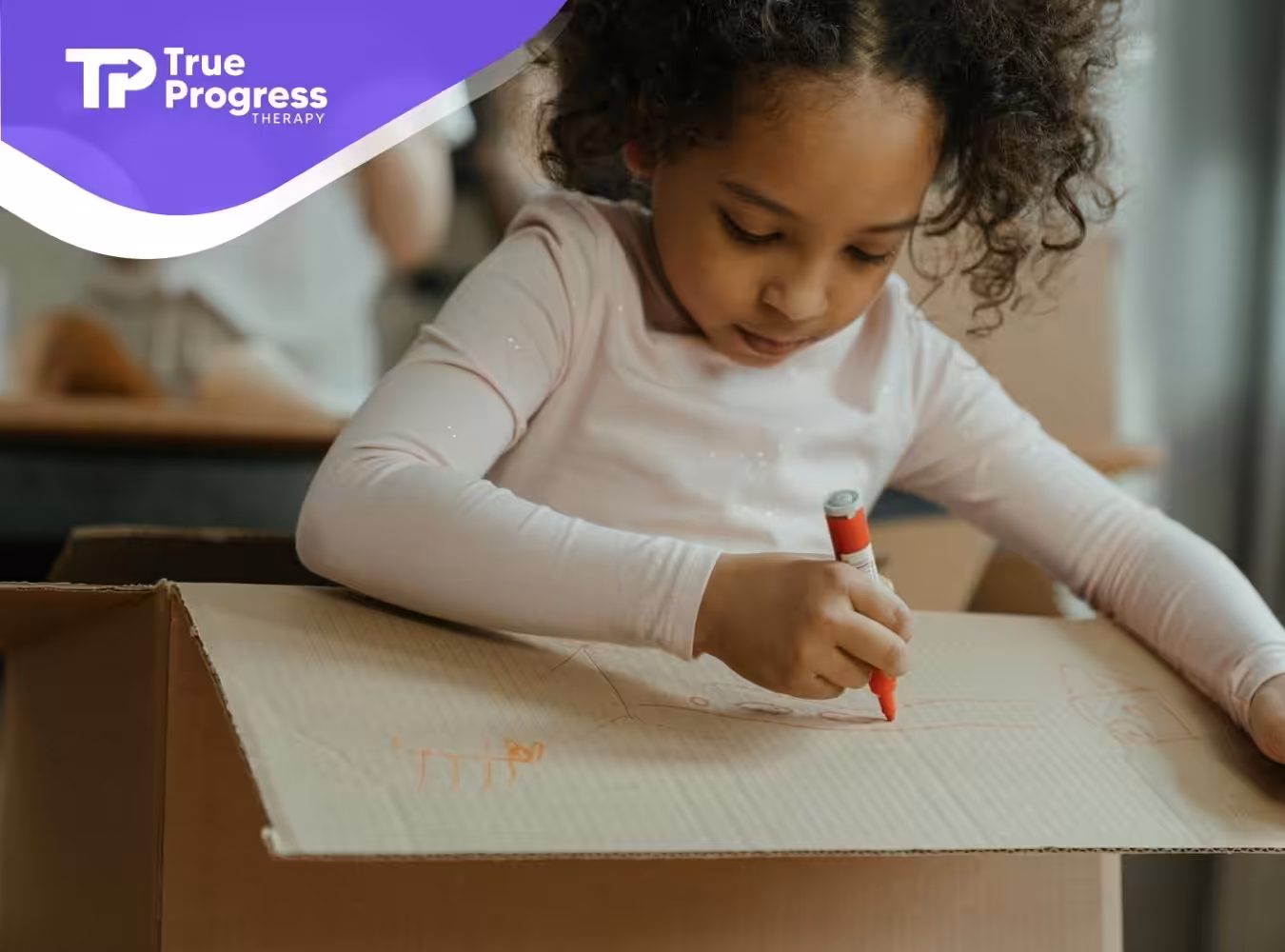 A girl with autism coloring on a cardboard box during a creative ABA therapy at a classroom in NJ.