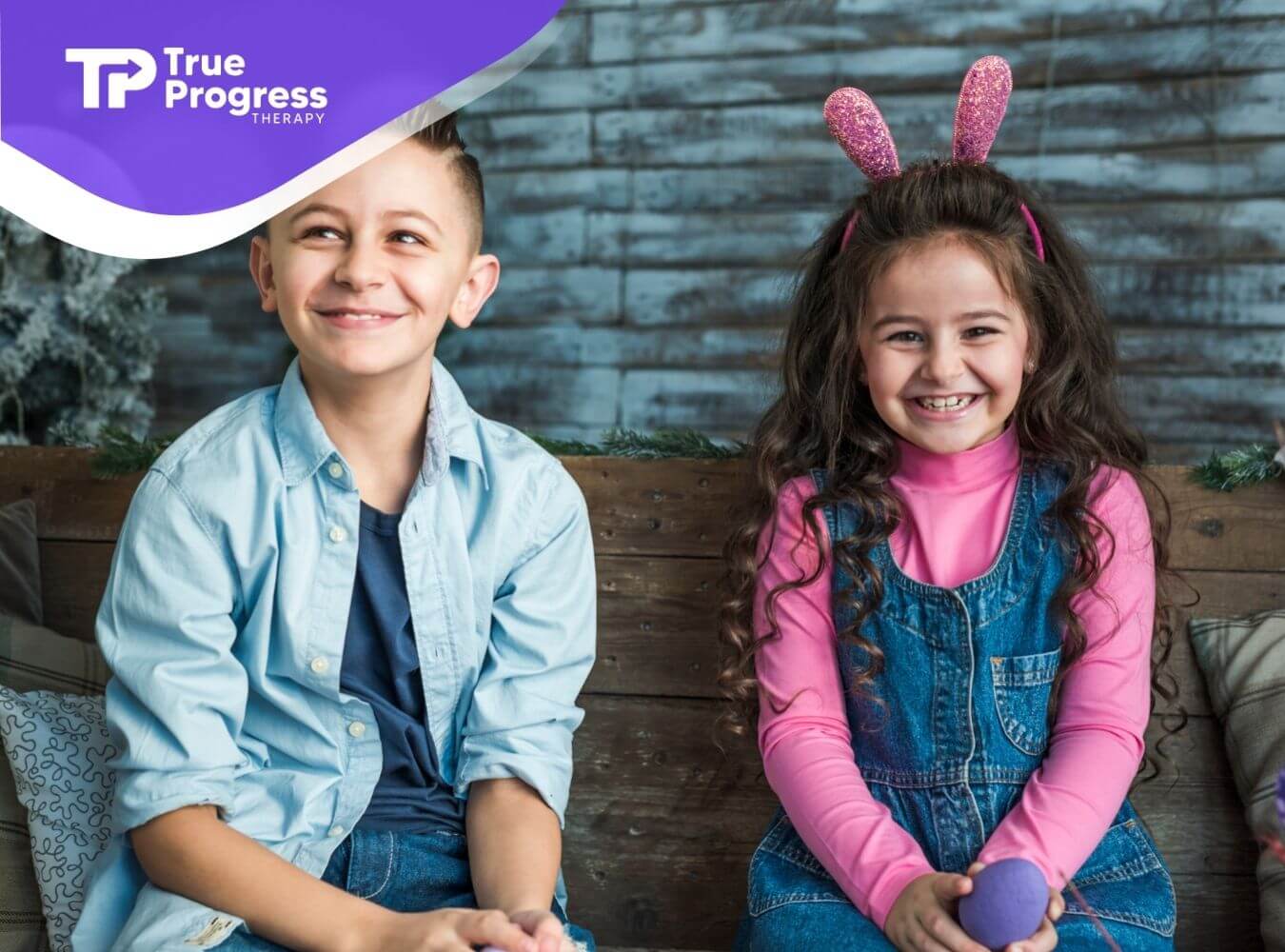 Two smiling children with autism sitting together in ABA therapy.