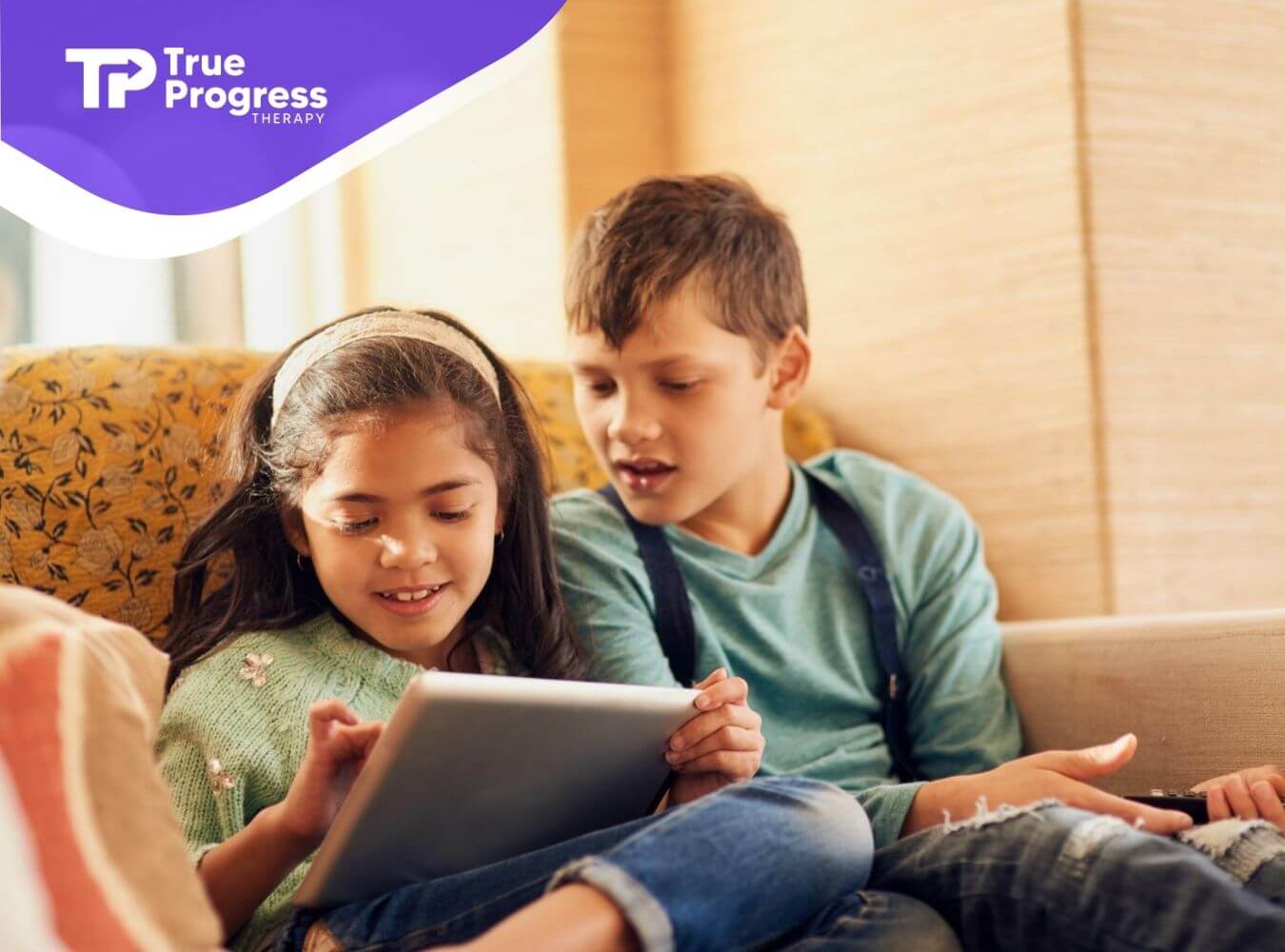 Two kids with autism using tablet together on couch.