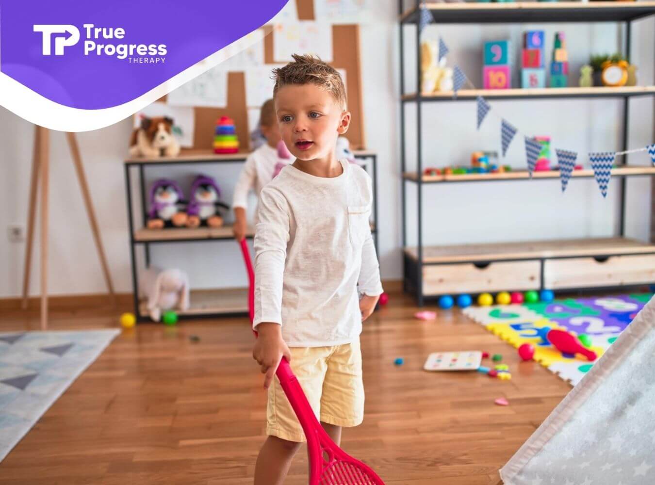 Young boy playing with toy racket in ABA therapy center.