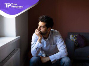 Man with autism sitting thoughtfully by the window, looking pensive and deep in thought.