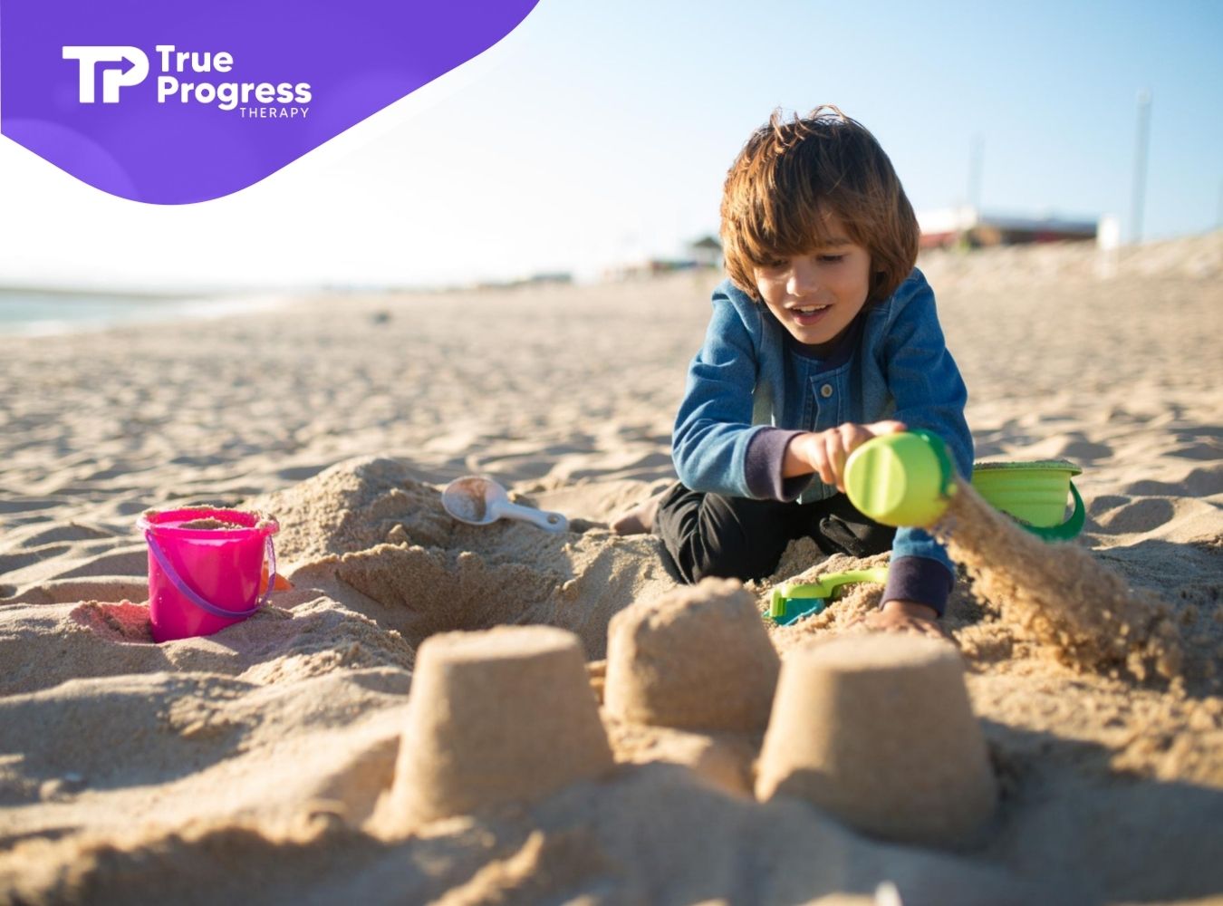 Child with autism building sandcastles on a sunny beach with colorful buckets and toys.